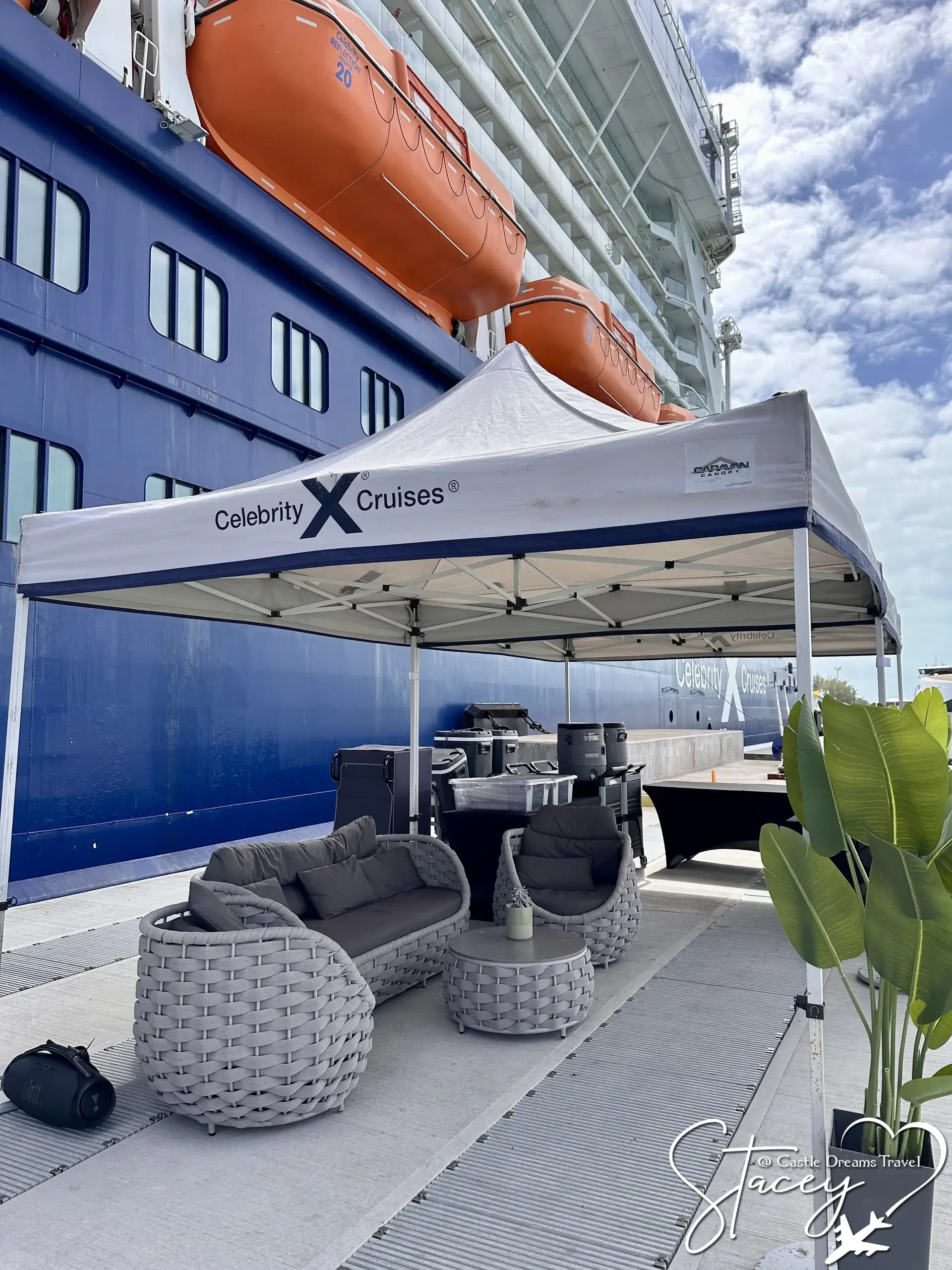 A shaded Celebrity Cruises lounge area with wicker seating set up dockside