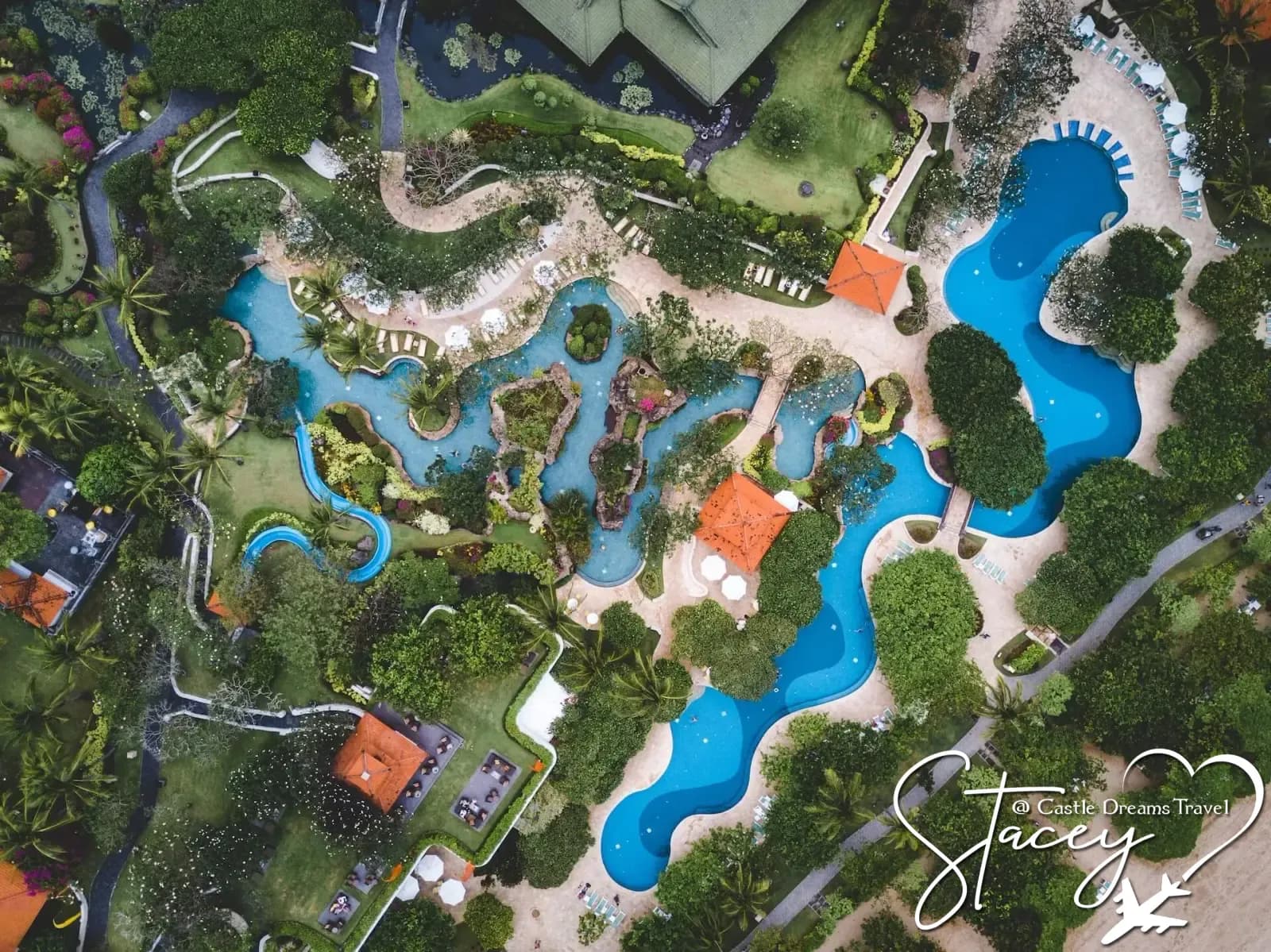 Aerial view of a tropical all-inclusive resort with winding pools among palm trees