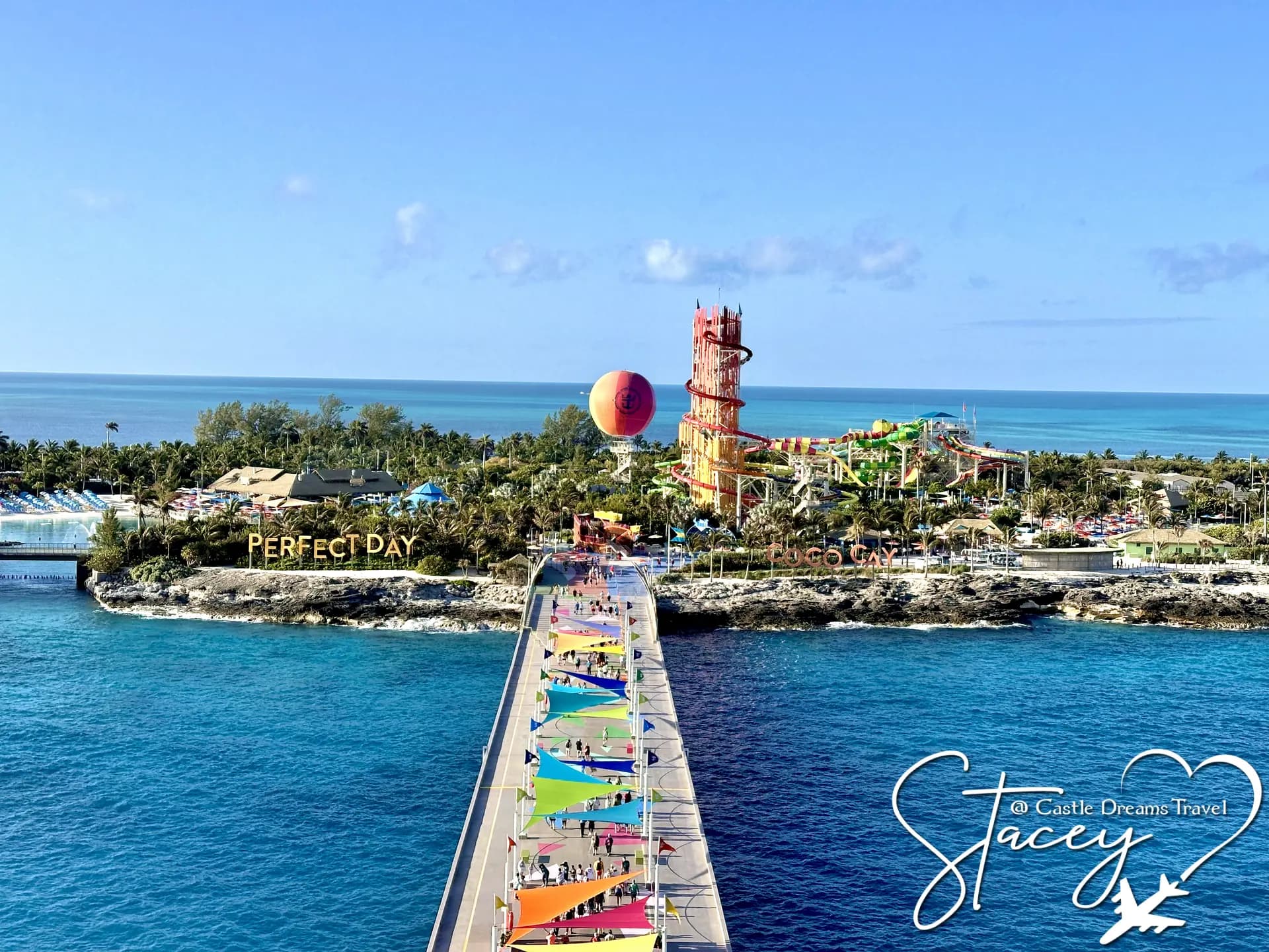 The colorful pier leading into Perfect Day at CocoCay, with the island's hot air balloon and turquoise water beyond