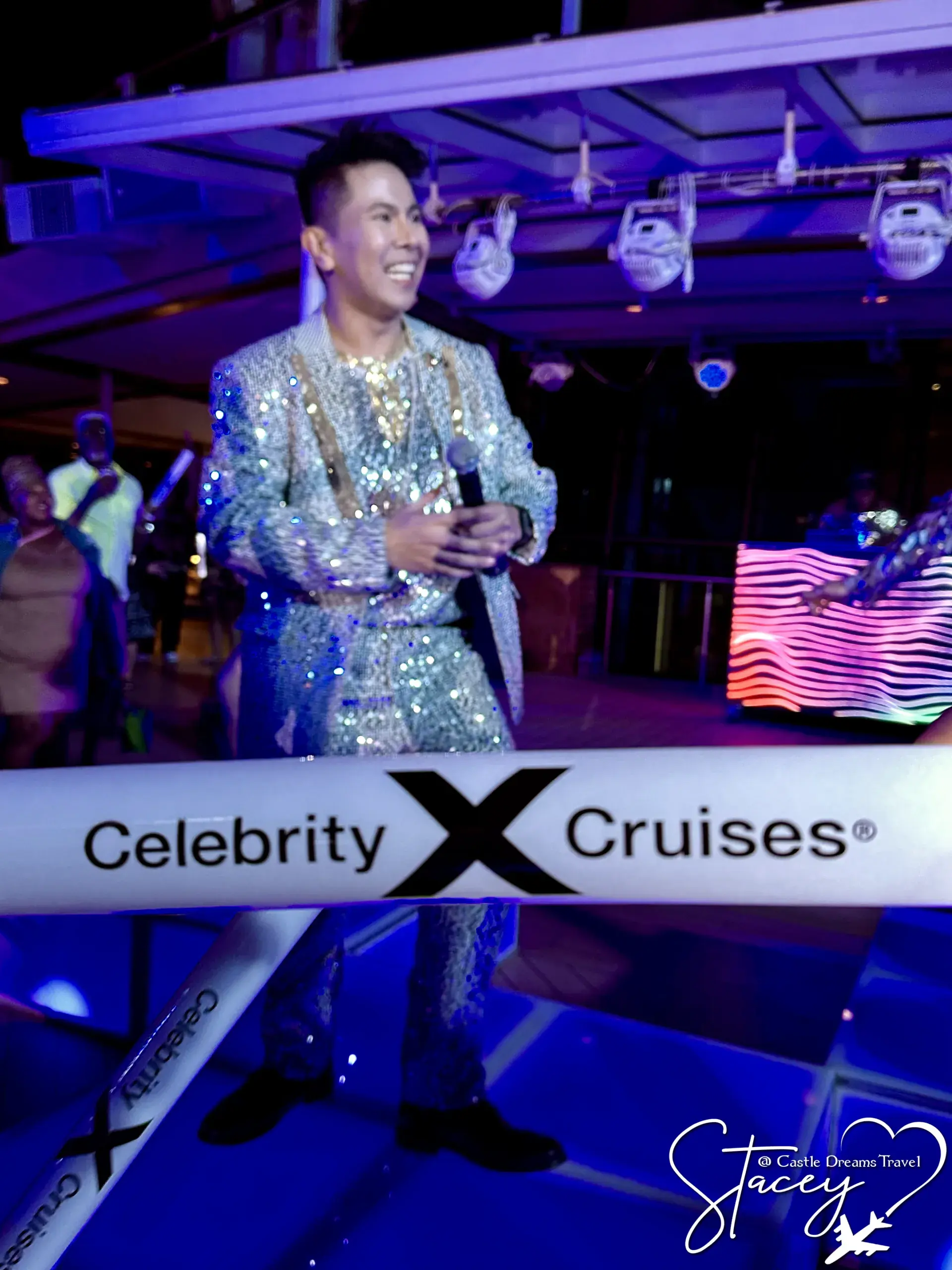 An entertainer in a sequined jacket performing with a microphone in a Celebrity Cruises onboard lounge