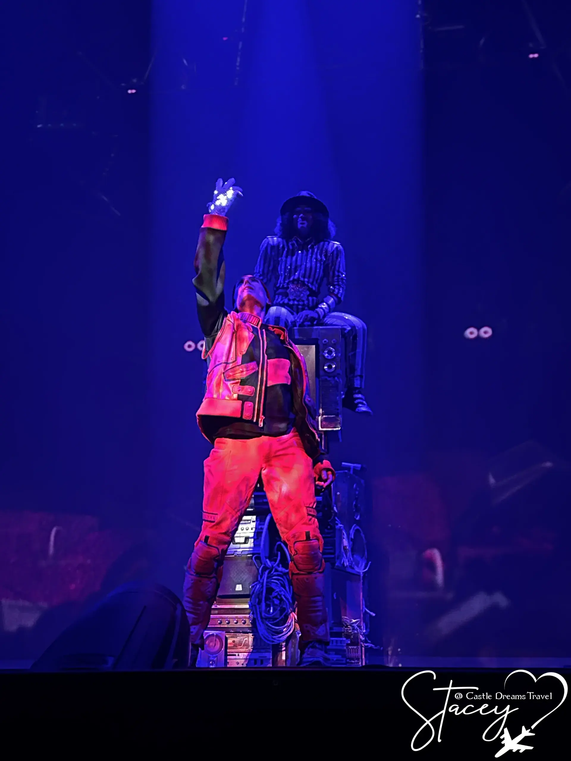 A performer raising an arm on a blue-lit stage during a Las Vegas production show