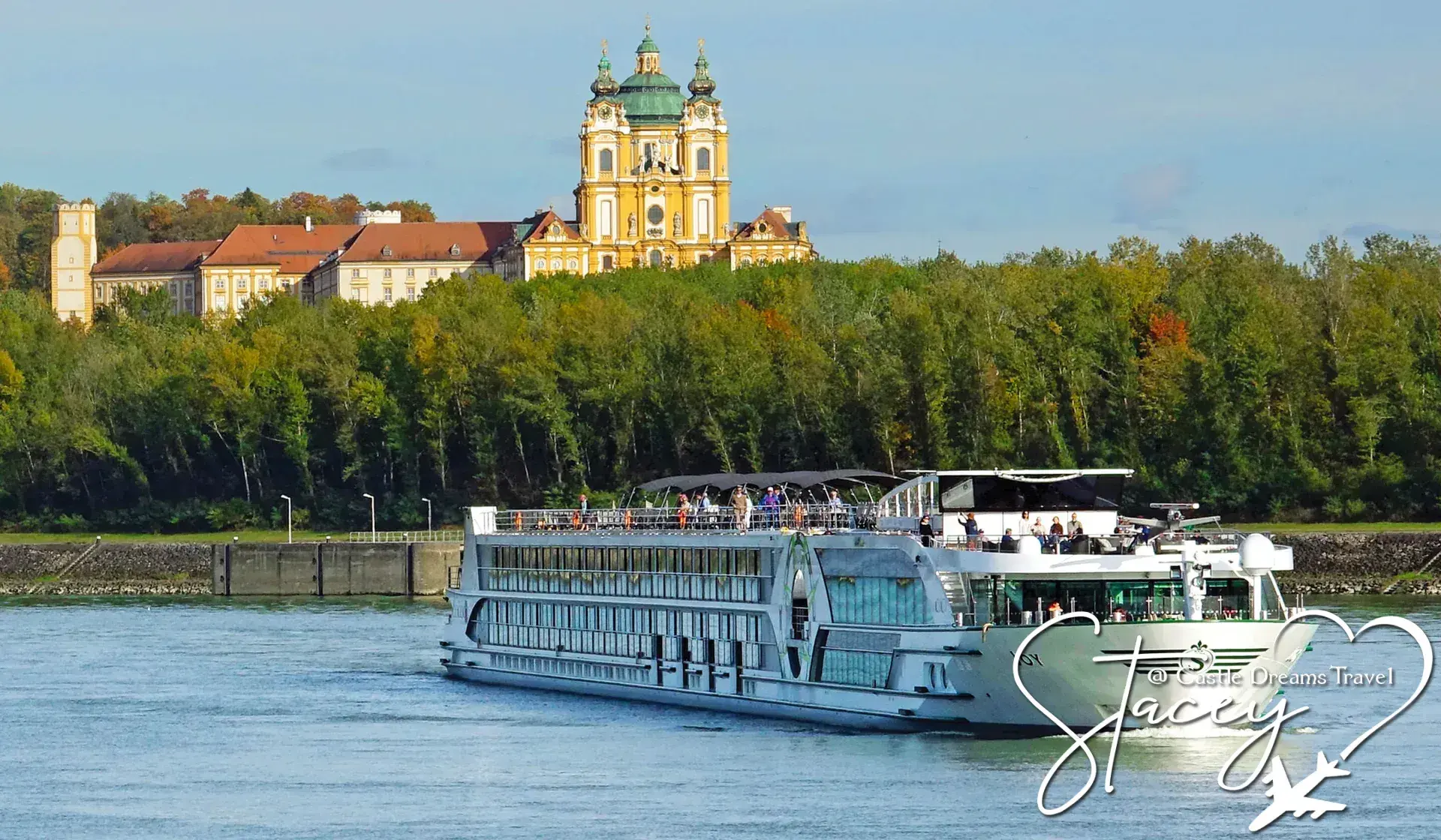 River cruise ship on the Danube passing below a hilltop baroque abbey