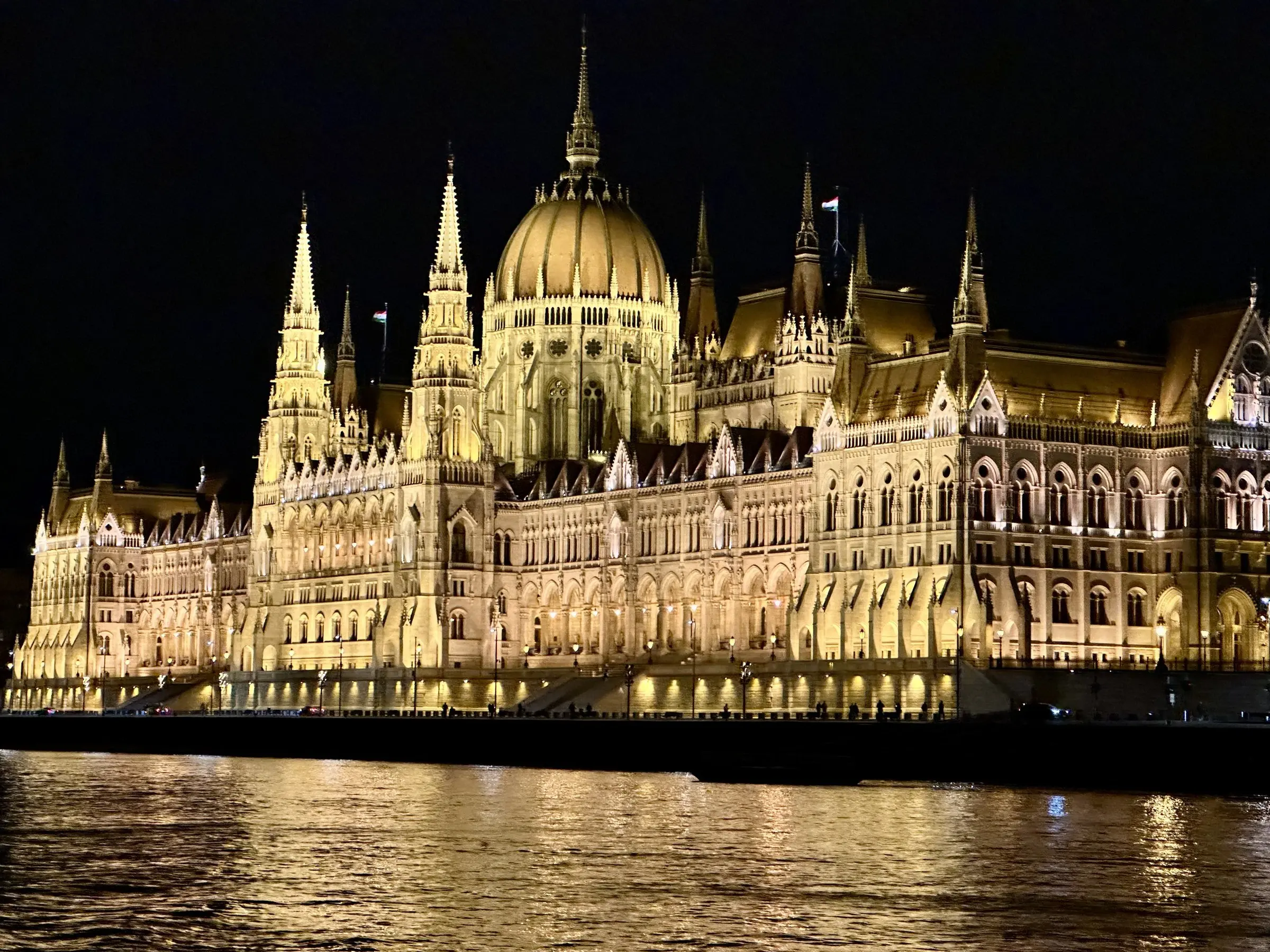 The Hungarian Parliament Building lit gold at night, reflected in the Danube, Budapest