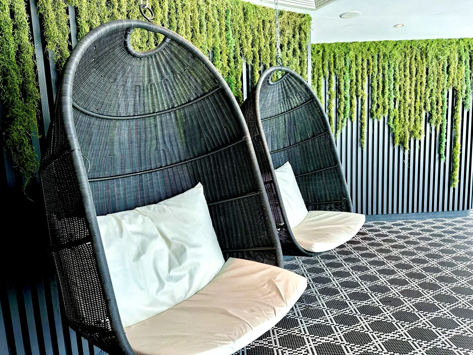 Hanging wicker cabana chairs against a living green wall aboard a Celebrity ship