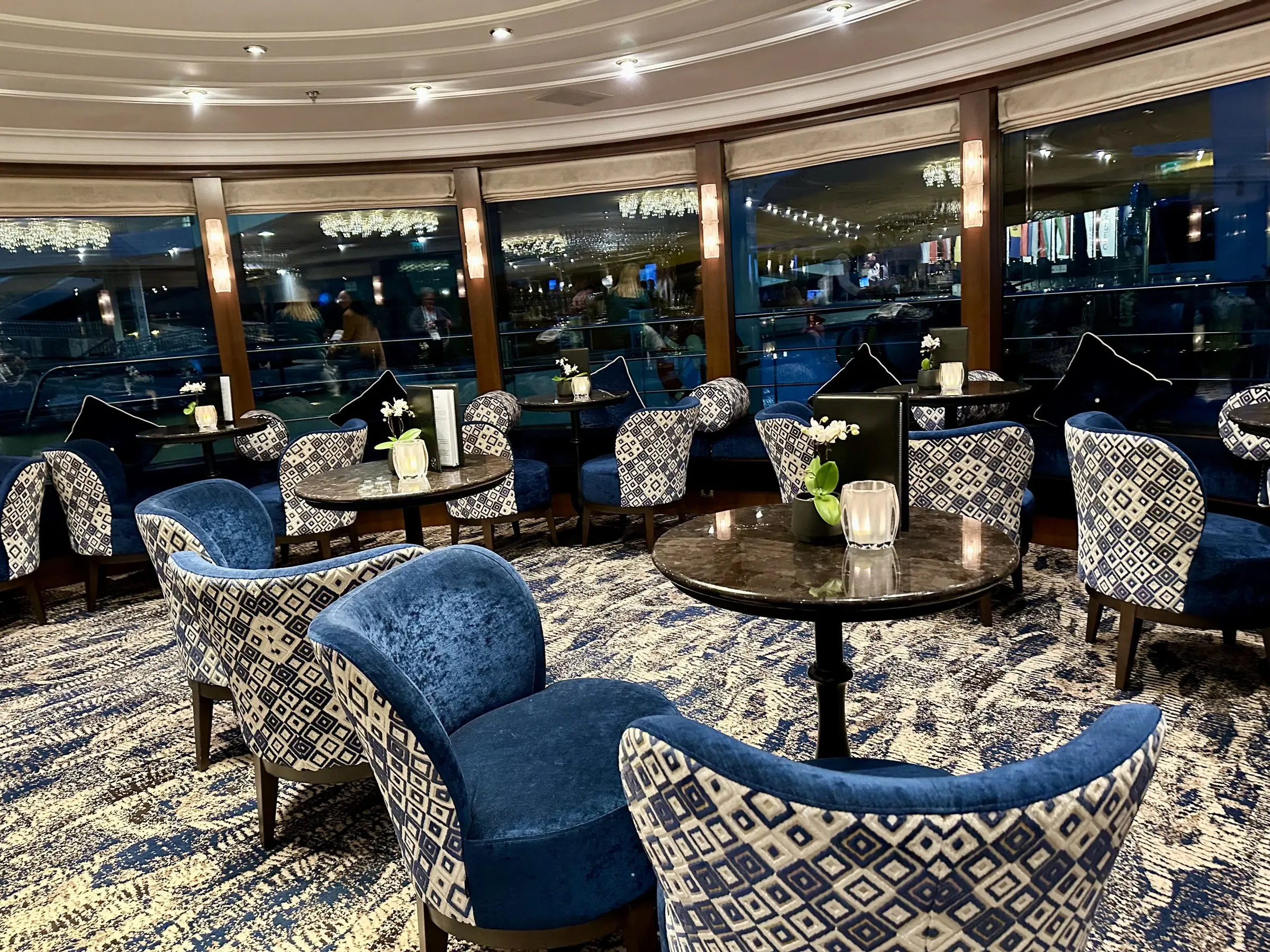 The navy velvet lounge aboard a Tauck river ship, lit by evening windows