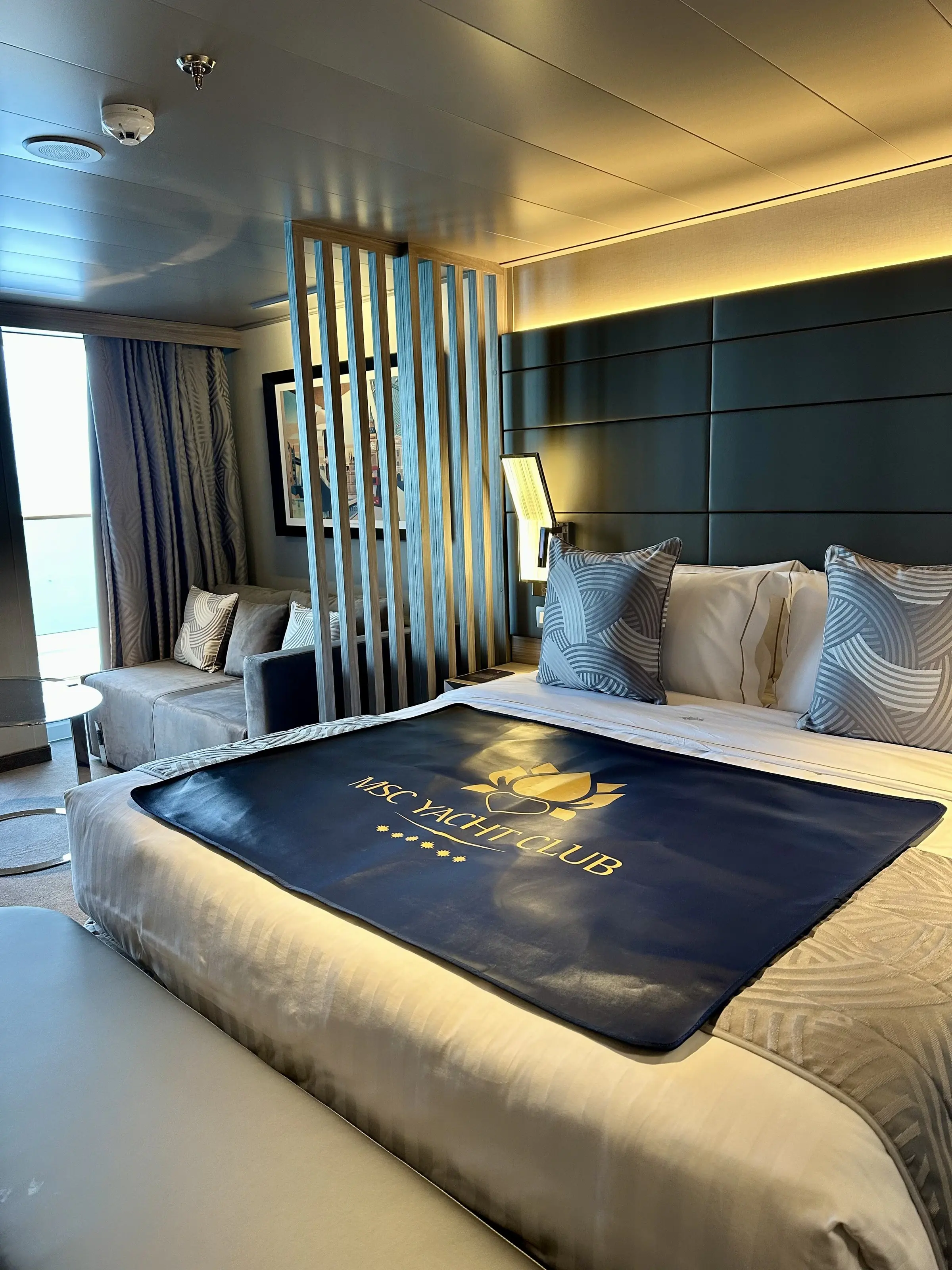 An MSC Yacht Club suite bed dressed with the Yacht Club throw
