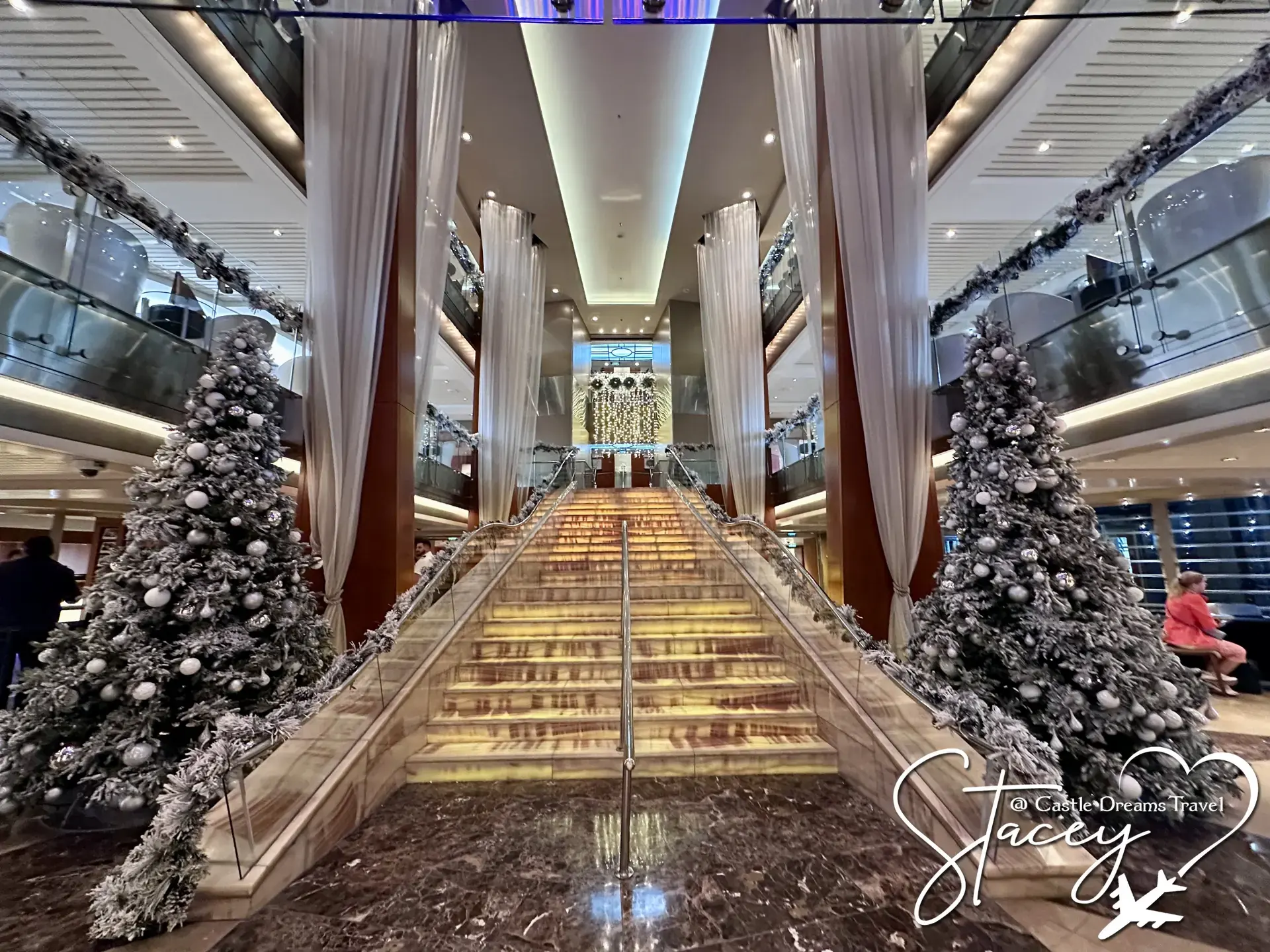 Grand staircase lined with flocked Christmas trees aboard a cruise ship