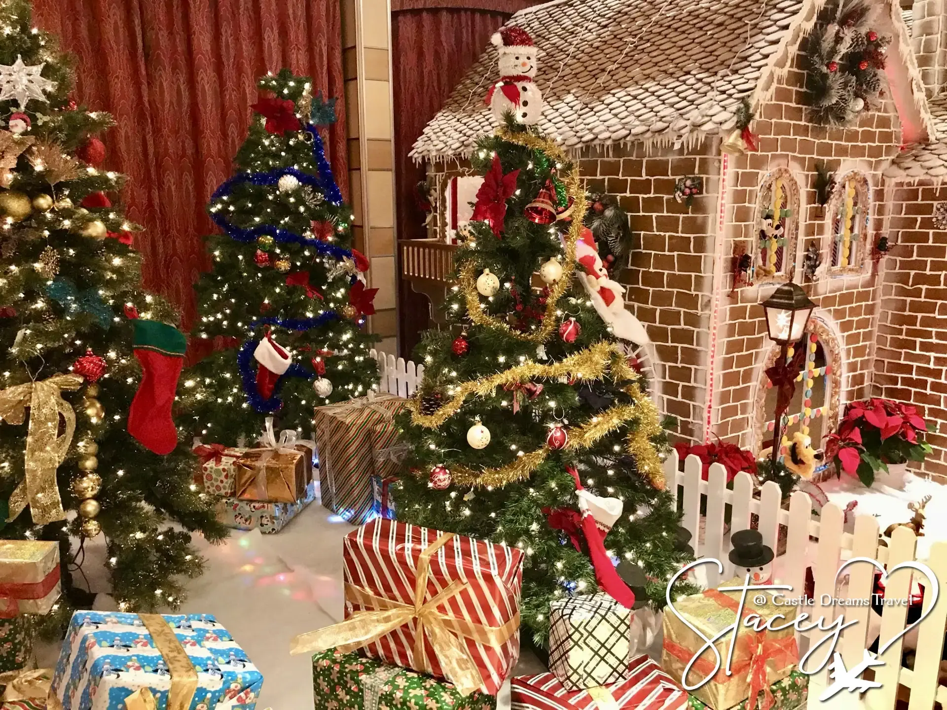 Decorated Christmas trees and wrapped presents beside a gingerbread house on a Disney cruise ship