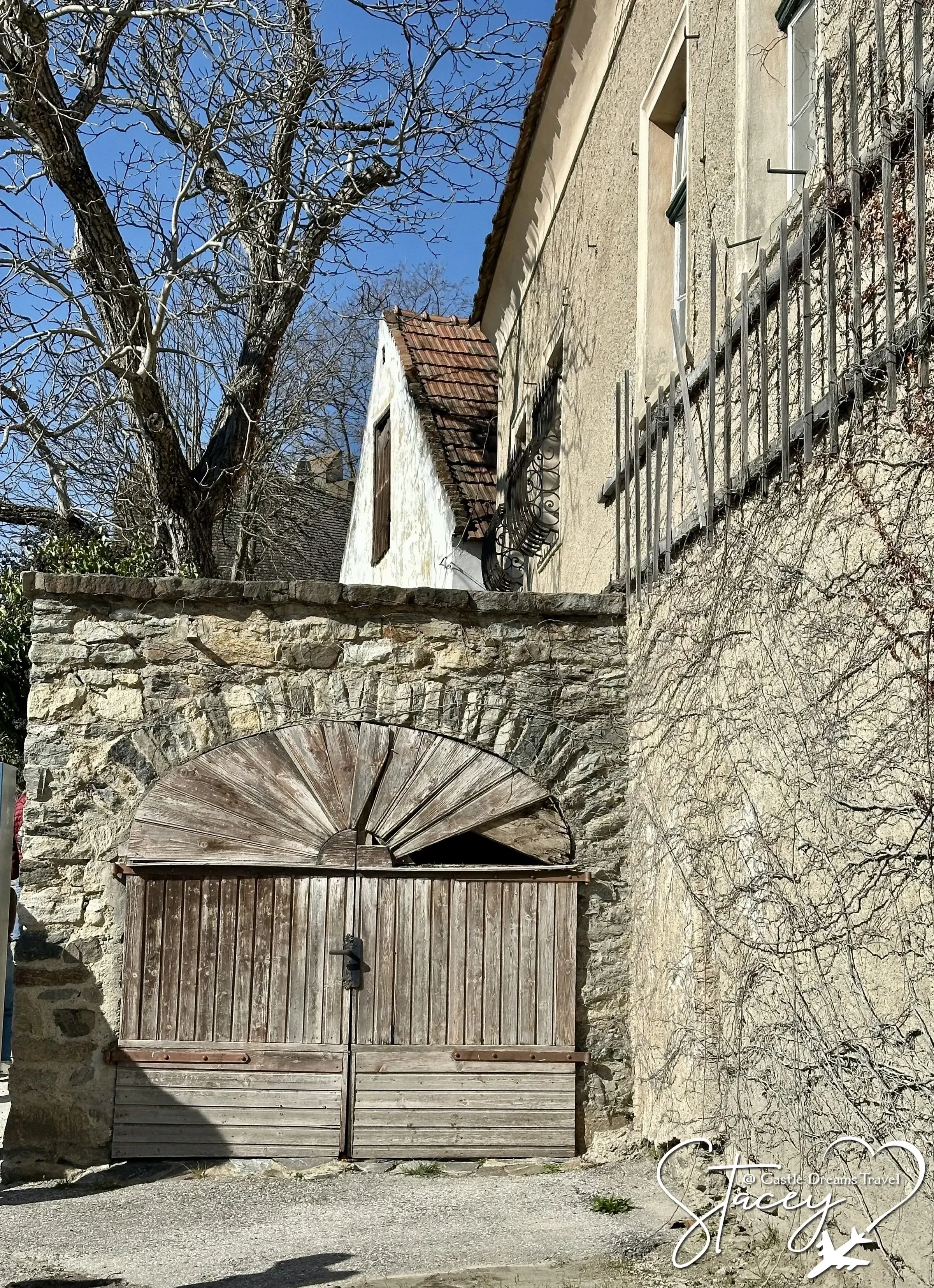 A weathered wooden gate set into an old stone wall in a Dürnstein lane