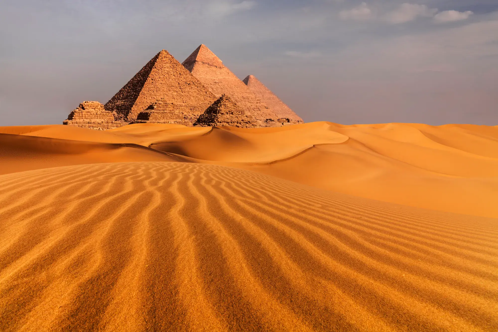 The Pyramids of Giza rising over the desert sand at sunset near Cairo, Egypt